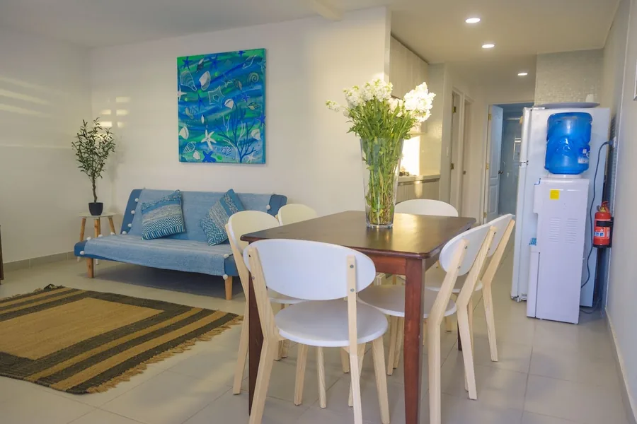 Living comedor del Departamento 1 con futón azul y mesa para seis